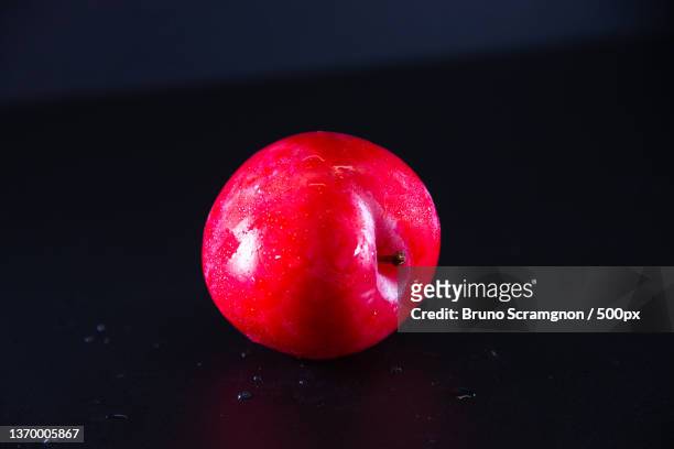 fresh red plum in black background,close-up of red apple against black background,rio de janeiro,brazil - orgânico stockfoto's en -beelden