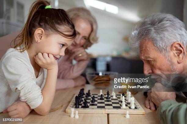 close up of grandparents teaching a granddaughter how to play chess - schaken stockfoto's en -beelden