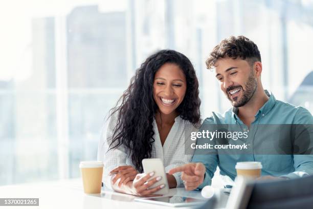 empresario y empresaria mirando un teléfono móvil. - coworker fotografías e imágenes de stock