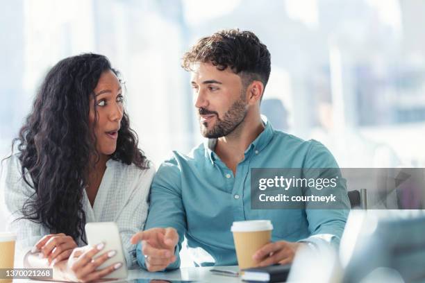 businessman and businesswoman looking at a mobile phone. woman has a shocked look on her face. - couple in surprise stock pictures, royalty-free photos & images