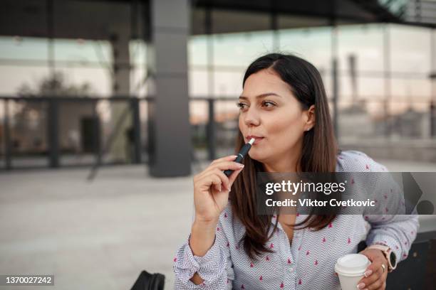 beautiful businesswoman taking a coffee and cigarette break from the office - e cigarettes stock pictures, royalty-free photos & images