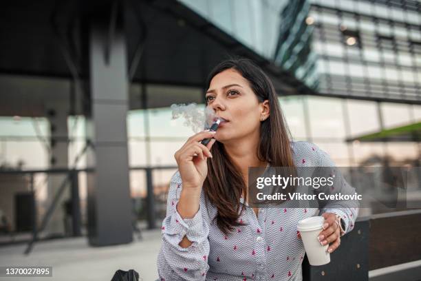 オフィスからコーヒーとタバコの休憩を取る美しいビジネスウーマン - electronic cigarette ストックフォトと画像