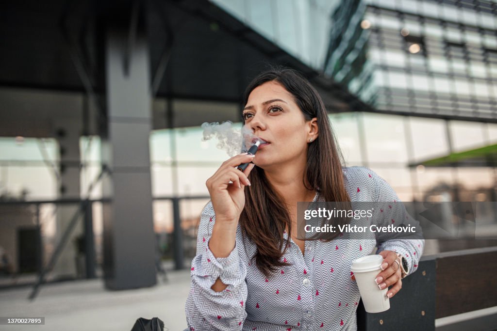 Bela empresária tomando café e pausa para fumar do escritório