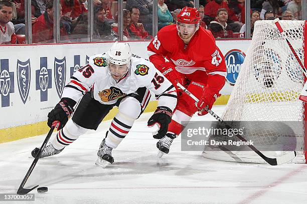 Andrew Brunette of the Chicago Blackhawks controls the puck while Darren Helm of the Detroit Red Wings follows after during an NHL game at Joe Louis...