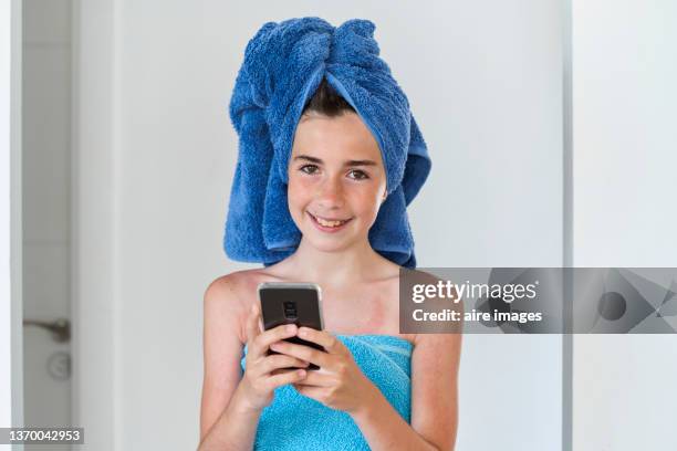 cute 12 year old girl wrapped in clean blue towels while using her cell phone in hotel room. - girls 12 year old pic 個照片及圖片檔