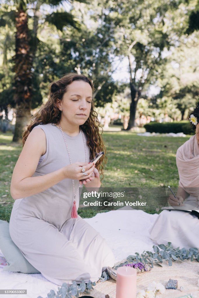 Woman of hispanic ethnicity with eyes closed smelling lignum sappan