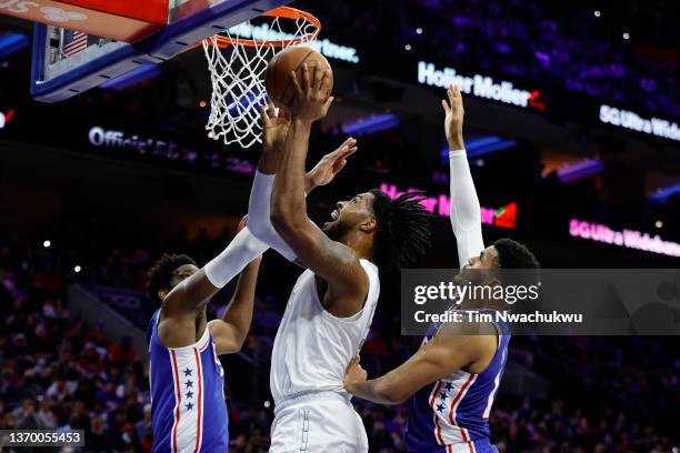 Derrick Favors of the Oklahoma City Thunder shoots betweek Joel Embiid and Tobias Harris of the Philadelphia 76ers during the third quarter at Wells...