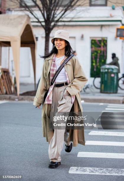 Guest is seen wearing beige trench coat, Prada bucket hat outside Proenza Schouler during New York Fashion Week on February 11, 2022 in New York City.