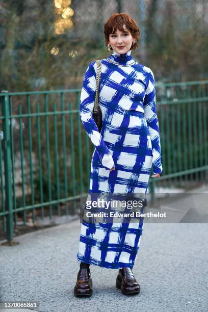 Alyssa Coscarelli wears a blue and white checkered turtleneck long slim dress with long sleeves, a black leather quilted bag, black leather shoes,...