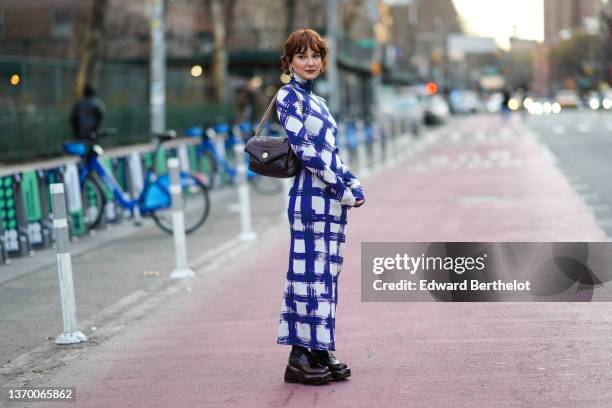 Alyssa Coscarelli wears a blue and white checkered turtleneck long slim dress with long sleeves, a black leather quilted bag, black leather shoes,...