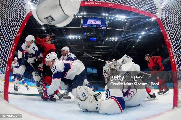 Goaltender Strauss Mann of Team United States and Jordan Weal of Team Canada watch the puck go toward the corner in the first period during the Men's...