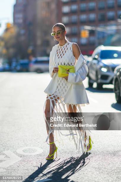 Leonie Hanne wears yellow sunglasses from Valentino, gold pendant earrings from Valentino, a gold large chain necklace, a white checkered cut-out...