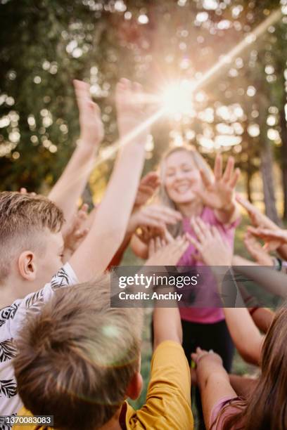 shot of a group of children giving each other a high five at summer camp - summer camp kids stock pictures, royalty-free photos & images