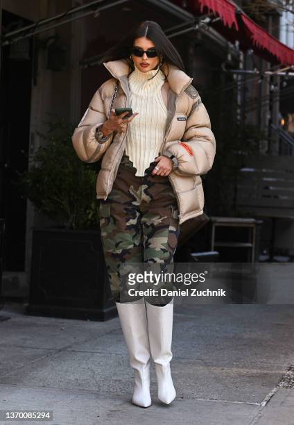 Guest is seen wearing a tan puff coat, cream sweater, camo pants and white boots outside the Bronx and Banco show during New York Fashion Week A/W...