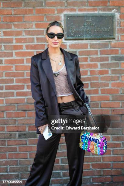 Guest wears black sunglasses, gold earrings, silver and diamonds rings, a silver chain necklace, a gold large chain pendant necklace, a pale gray...