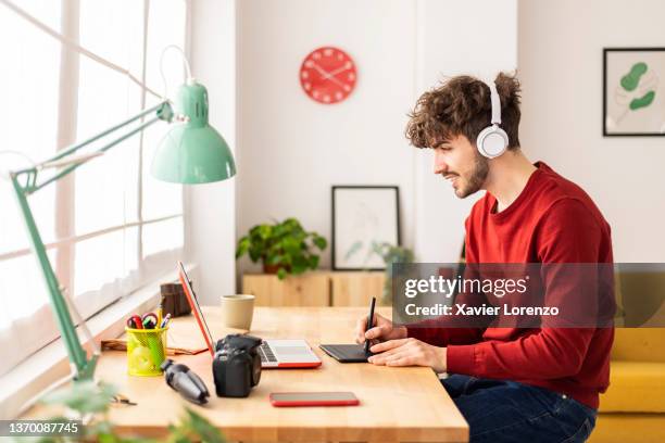 creative graphic designer using a tablet and pen while working on a project at home. - graphic designer stockfoto's en -beelden