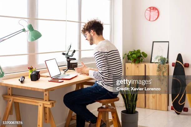 young using laptop while sitting at a desk - working at home desktop computer stock-fotos und bilder