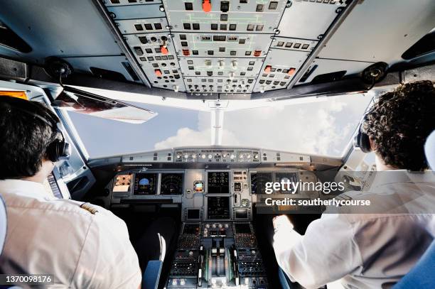 dos pilotos en la cabina de un moderno avión a reacción de pasajeros. - pilotar fotografías e imágenes de stock