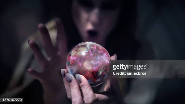 魅惑的な女性占い師は、内部の魔法の、輝くほこりでガラス球を保持しています - 占い師 ストックフォトと画像