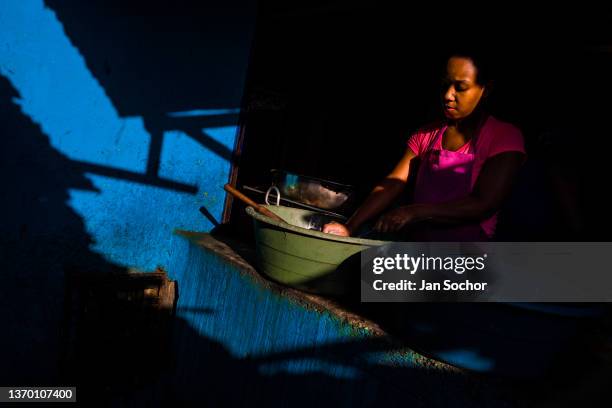 Young Afro-Colombian woman washes the dishes at the end of a twelve-hour shift in a street restaurant in the market of Bazurto on December 5, 2018 in...