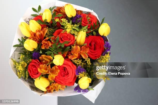 yellow tulips and red roses bouquet against grey background - blumenstrauß stock-fotos und bilder