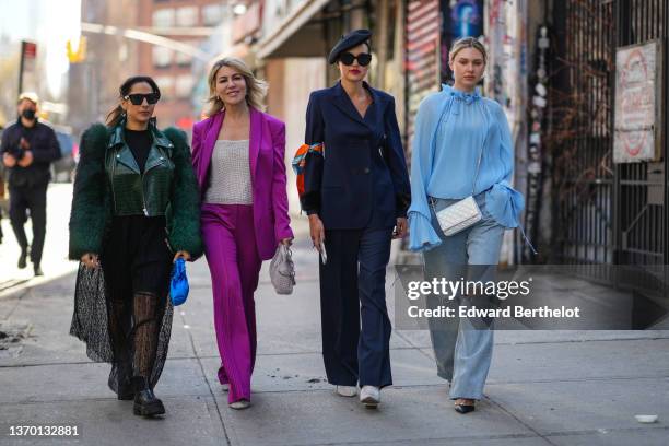 Samia Laaboudi wears sunglasses, green long fringed earrings, a black top, a green leather jacket with fluffy faux fur sleeves, a black ribbed top, a...