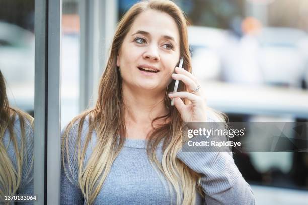 beautiful woman in her 30s chatting on her mobile phone in a city street - female worried mobile imagens e fotografias de stock