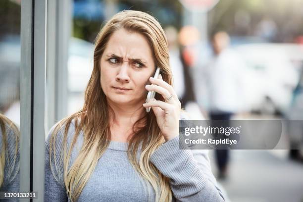 mulher bonita de 30 anos reage ao celular com choque e suspeita em rua da cidade - suspicion - fotografias e filmes do acervo