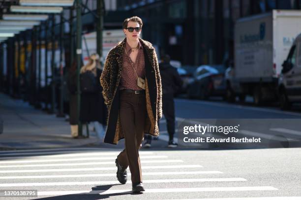 Guest wears sunglasses, gold chain necklace, a brown with beige polka dots print pattern shirt, a beige suede crossbody bag, a black and beige...