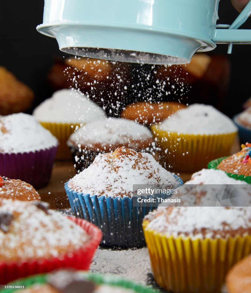 Sifting powdered sugar on cupcakes