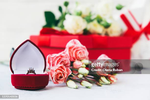 beautiful engagement ring in red box near bouquet of roses and red gift box - ring around the rosy stock pictures, royalty-free photos & images