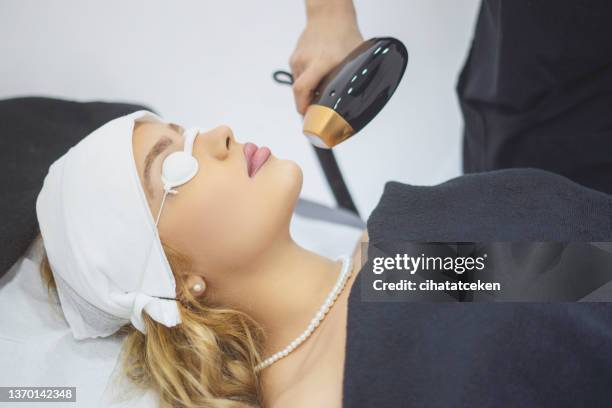 beautician giving epilation laser treatment on woman's face - facelift stock pictures, royalty-free photos & images