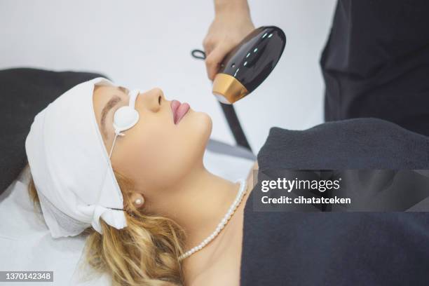 beautician giving epilation laser treatment on woman's face - beauty treatment stock pictures, royalty-free photos & images