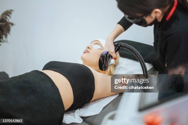 young woman is having hair removal treatment with medical laser on woman arm - wax strip stock pictures, royalty-free photos & images