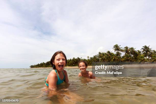 excited children playing in tranquil water in a tropical beach with coconut palm trees in alagoas, northeastern brazil - alagoas stock pictures, royalty-free photos & images