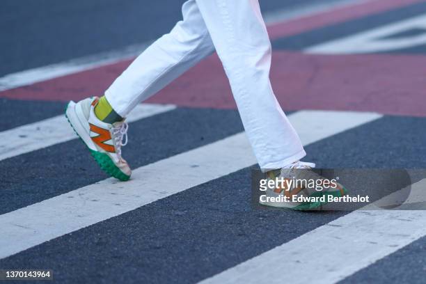 Guest wears white denim cigarette pants, green print pattern socks, a white leather with green and orange suede logo sneakers from New Balance,...
