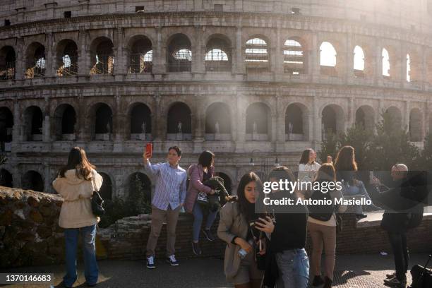 People take pictures near the Colosseum without wearing protective masks, on February 12, 2022 in Rome, Italy. The Italian government lifted...