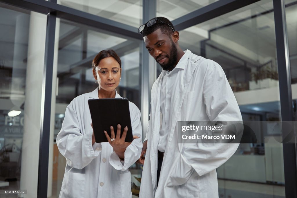 Shot of two scientists working together on a digital tablet
