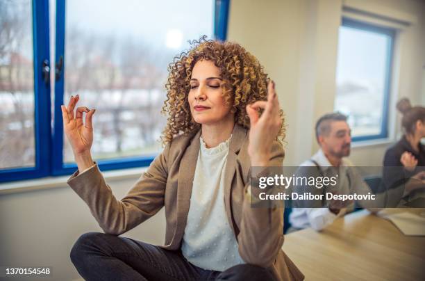 a group of businessmen meditate in the office. - bemiddeling stockfoto's en -beelden