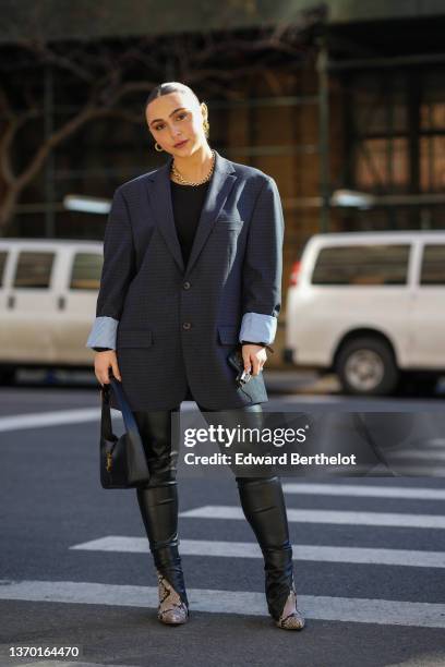 Guest wears gold earrings, a gold chain large necklace, a black t-shirt, a navy blue oversized blazer jacket, black shiny leather legging pants, a...