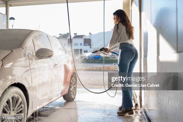 middle-age woman washing his car in a washing car station - car splashing water on people stock pictures, royalty-free photos & images