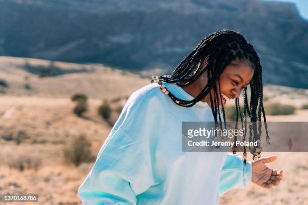 cute joyful portrait of a cheerful young african american woman laughing and standing on a footpath outdoors while getting some exercise in a desert recreational area near the colorado national monument - locs hairstyle stock pictures, royalty-free photos & images