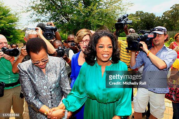 Oprah Winfrey leads Former President of South Africa Nelson Mandela's wife Graca Machel on her arrival at the inaugural graduation of the Class of...