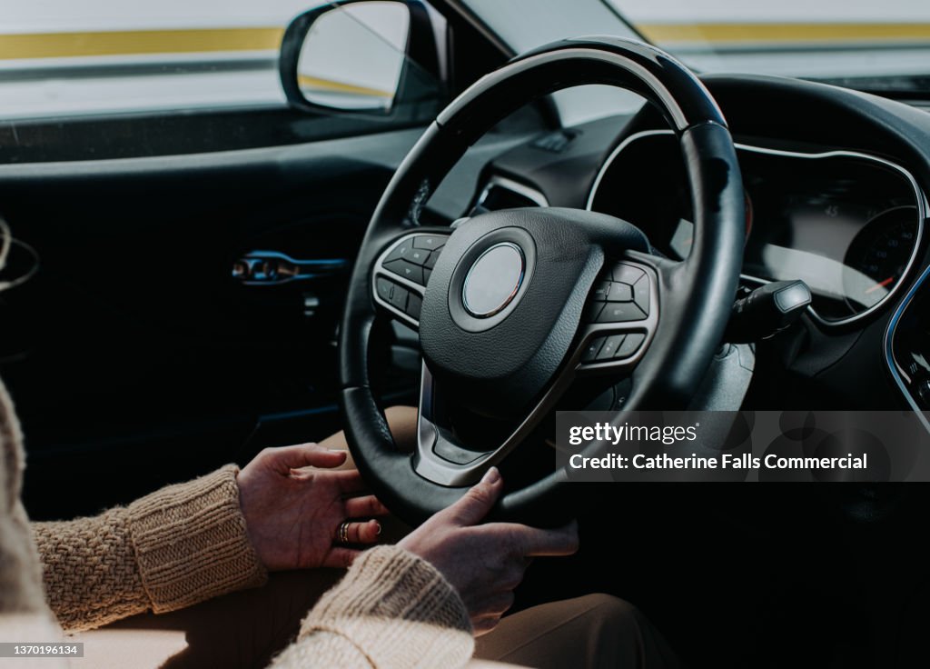 Female hands holding steering wheel in a Car