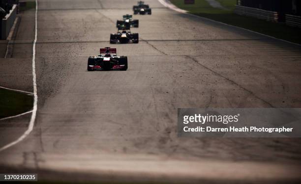 In back lit light, British McLaren Formula One team racing driver Jenson Button driving his MP4-28 racing car at speed towards Turn 15 of the circuit...