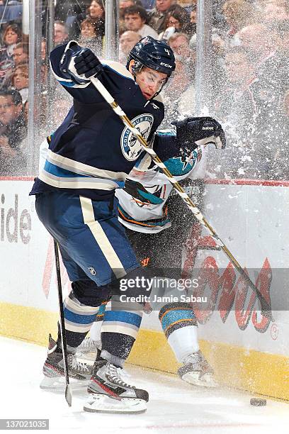 John Moore of the Columbus Blue Jackets checks Logan Couture of the San Jose Sharks into the boards while battling for control of the puck during the...