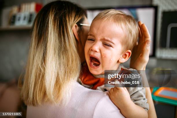 baby boy is crying while mother holding him in arms - toddler crying stock pictures, royalty-free photos & images