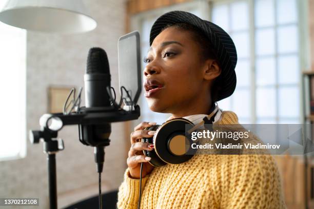 woman singing into a large microphone - professional singer stock pictures, royalty-free photos & images