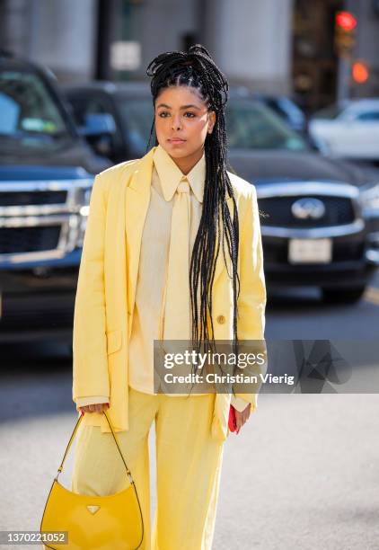 Guest is seen wearing yellow blazer and pants, Prada bag, tie outside PatBo during New York Fashion Week on February 12, 2022 in New York City.