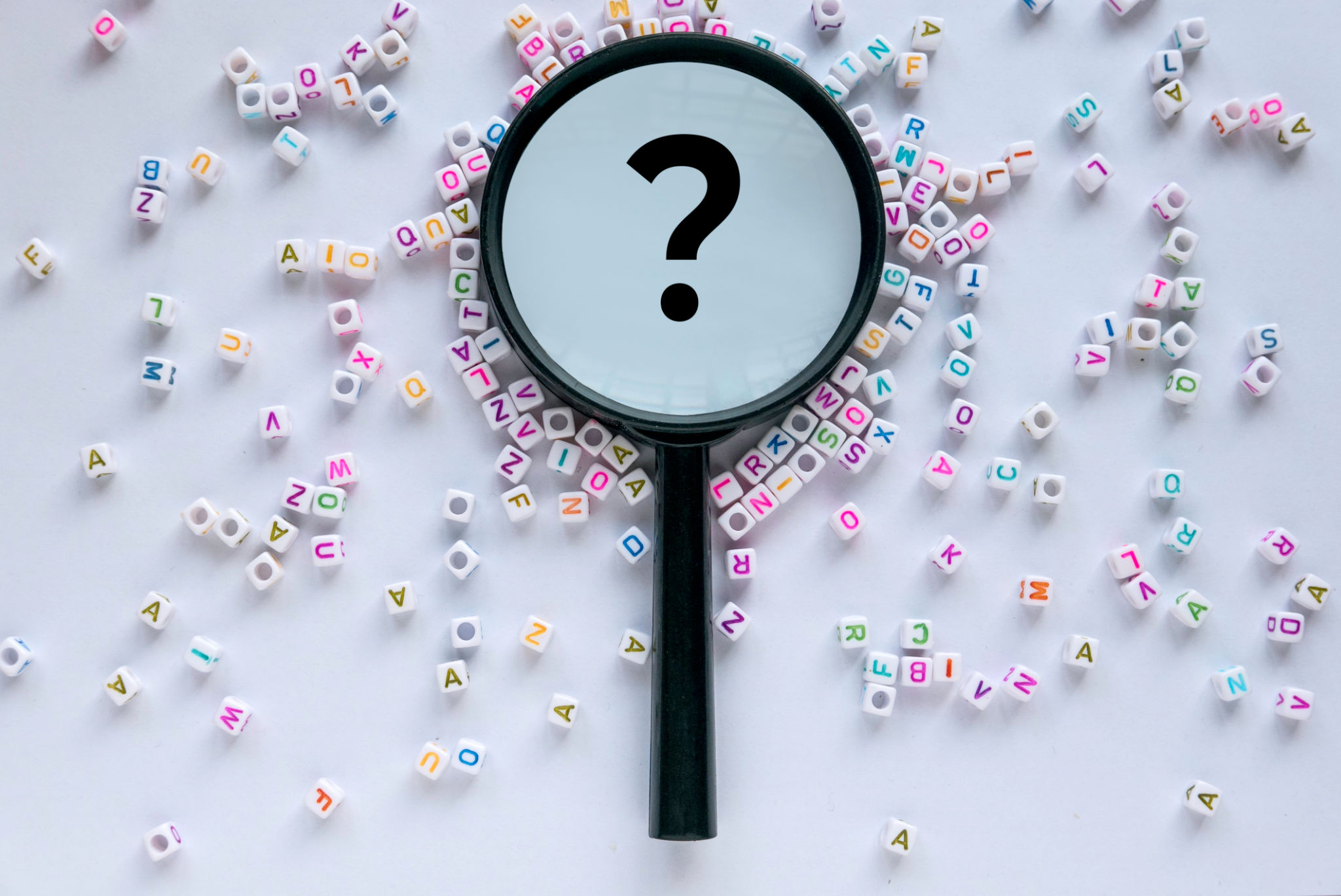 Questions and answers concept. Alphabet beads with magnifying glass with question symbol in it on white background. Questions and answers concept. Alphabet beads with magnifying glass with question symbol in it on white background.